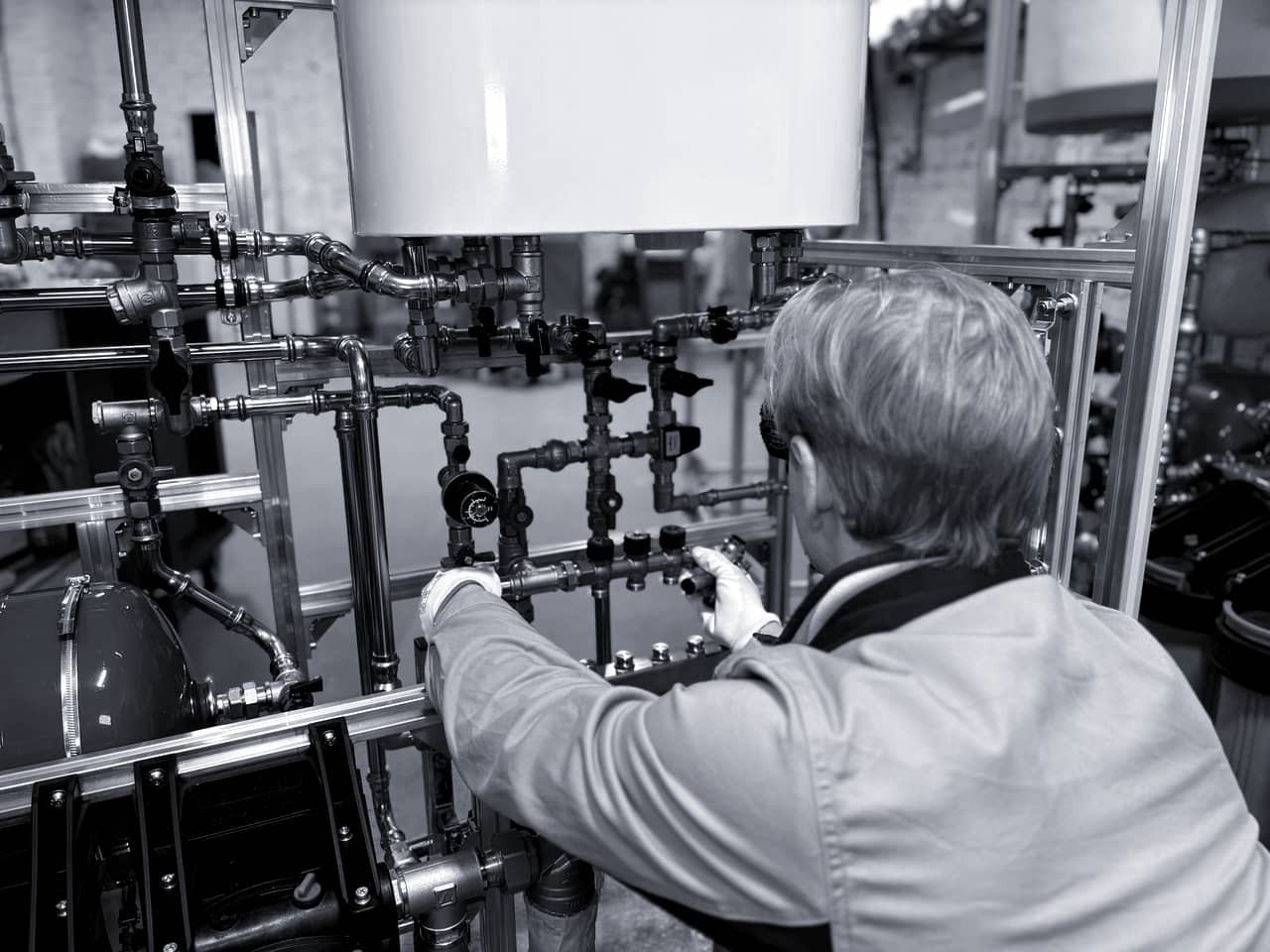 A UK heating engineer working on pipework and a domestic heating system.